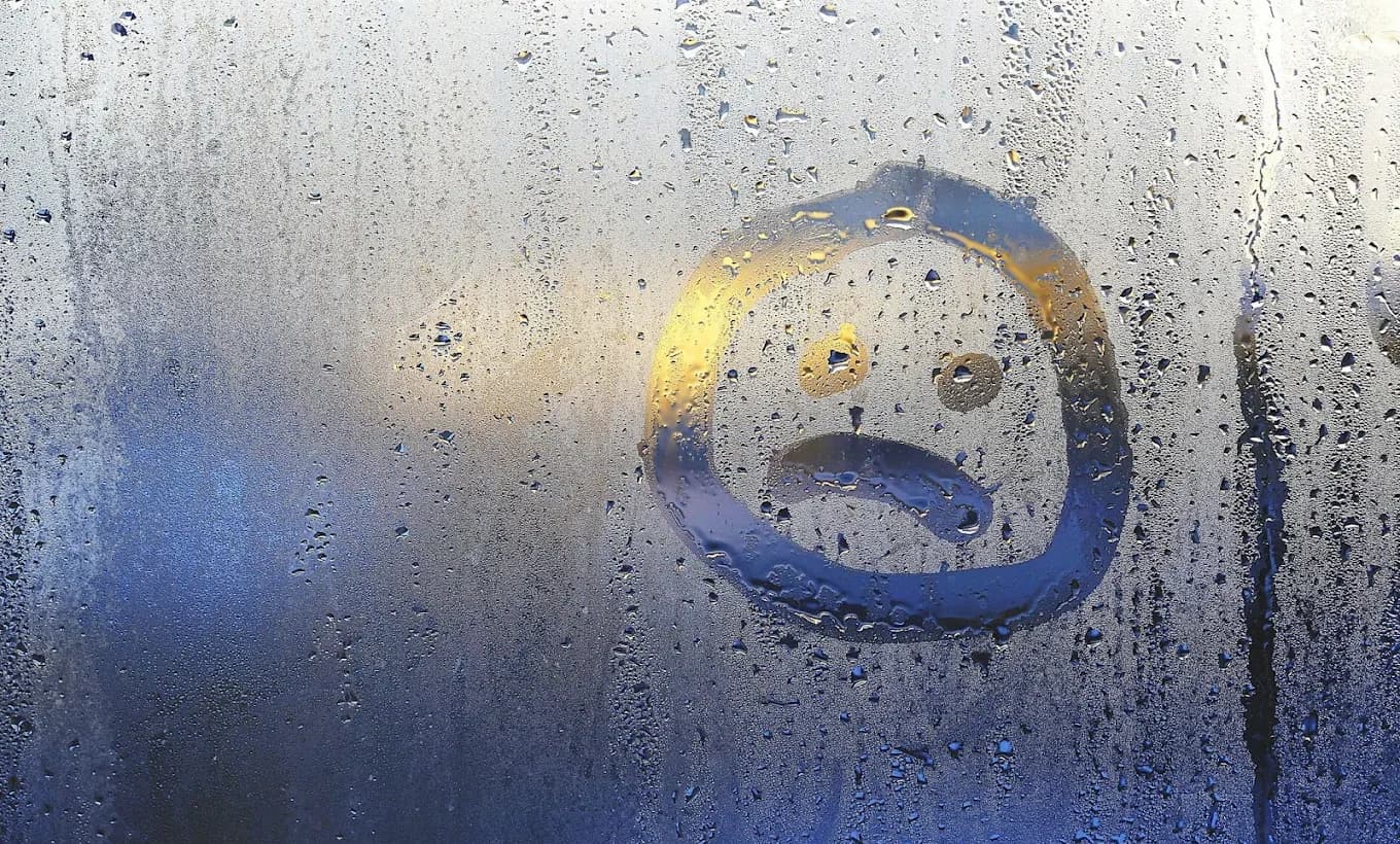 Sad face drawn in window condensation