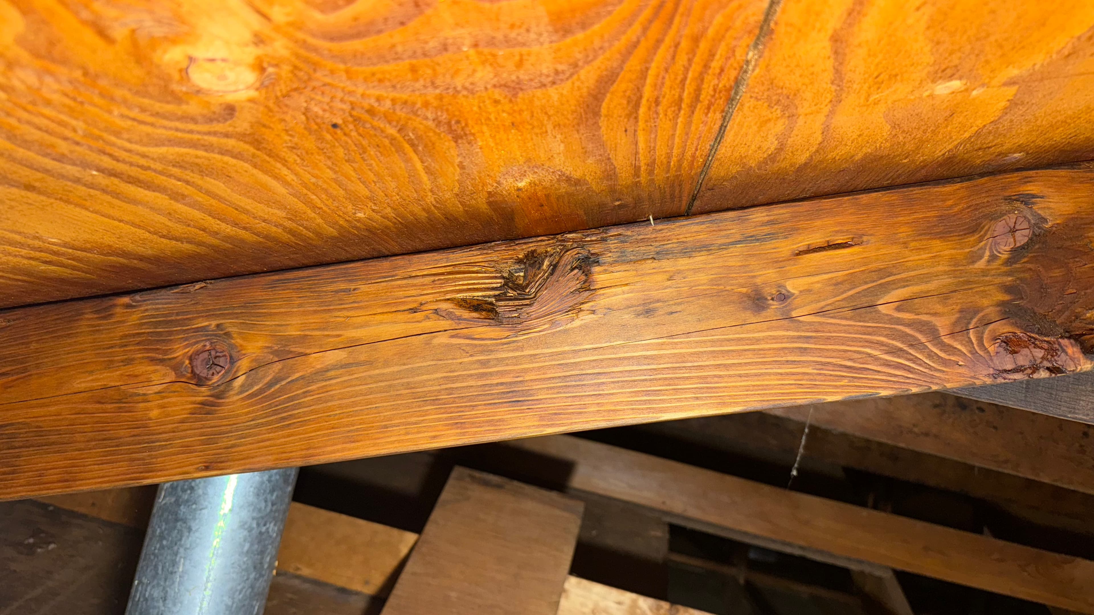 After: Mold growth around attic joist near metal pipe penetration — cleaned and treated