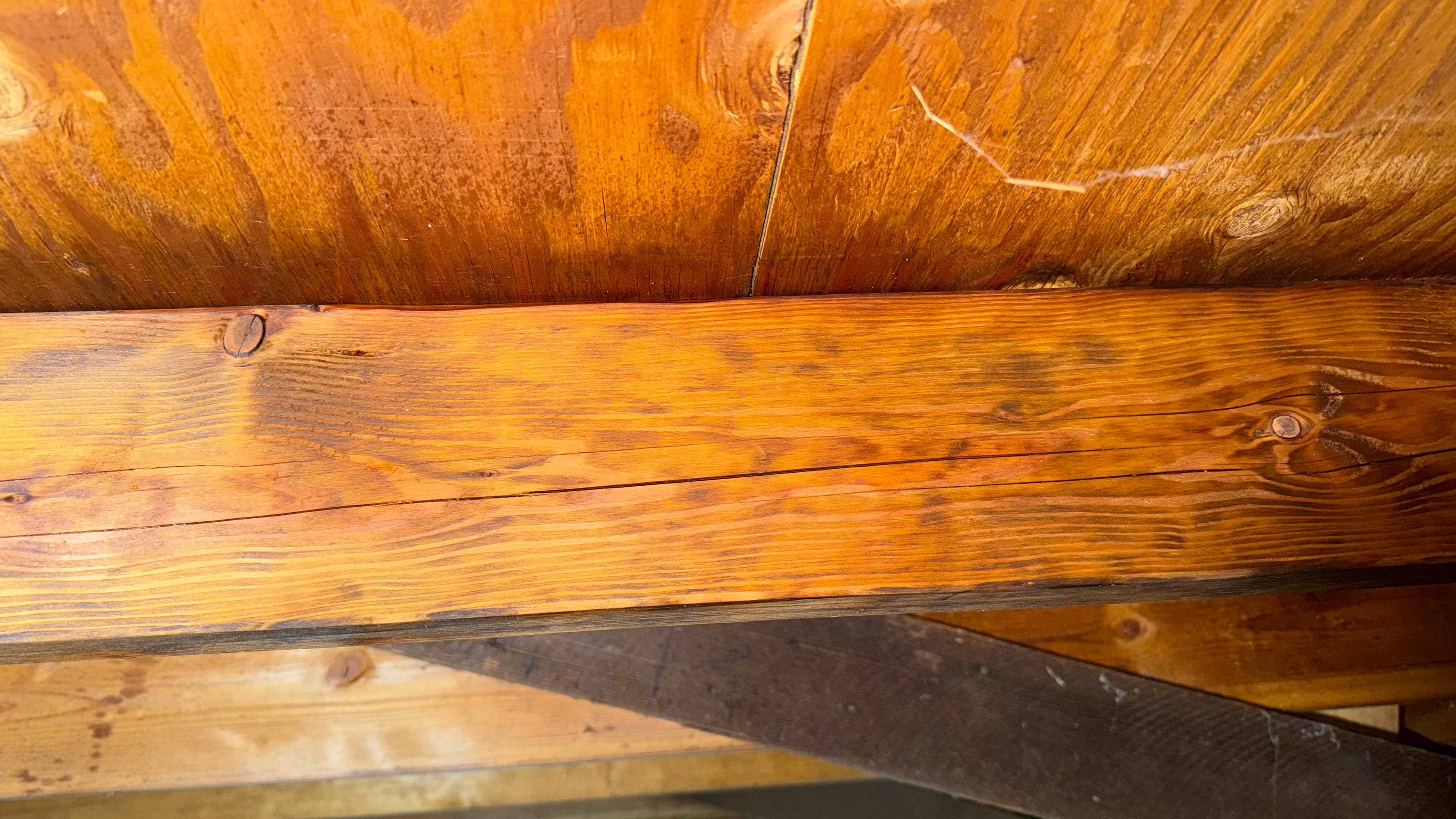 After: Dark mold patches on attic rafter eliminated — warm, clean wood tone restored