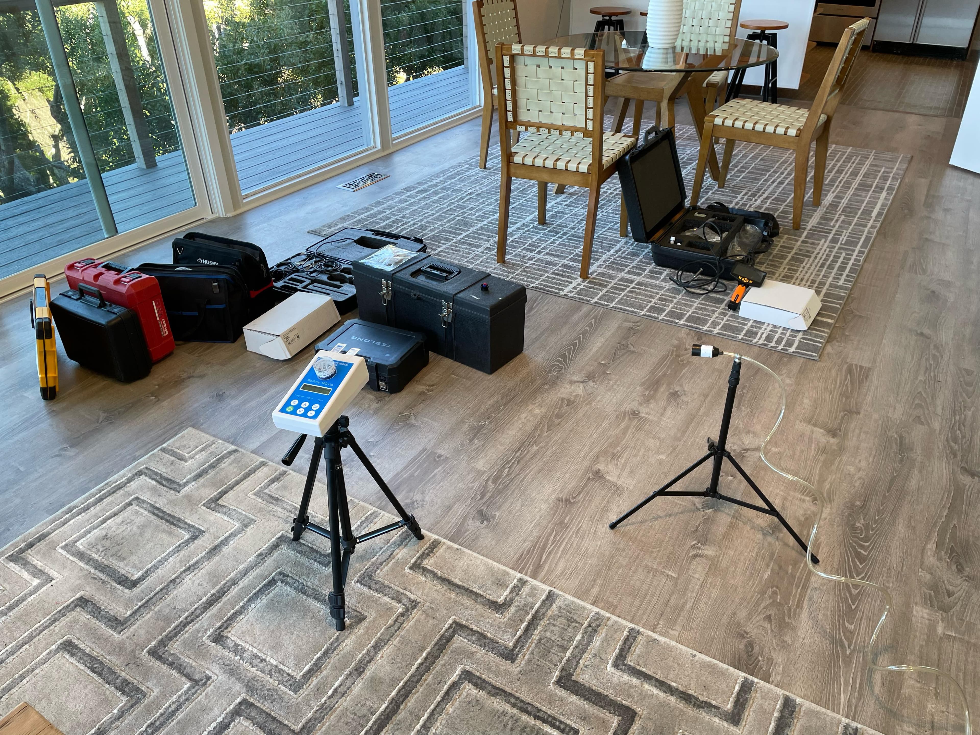 Full spread of professional mold inspection equipment laid out in a home living room — air sampling pumps, moisture meters, borescope, and protective cases